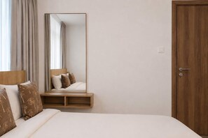 Ein Hotelzimmer mit einem Bett, einem Nachttisch aus Holz, einem Spiegel und einer Tür.