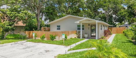 A single-story house with a front porch, a driveway, and a well-maintained lawn.