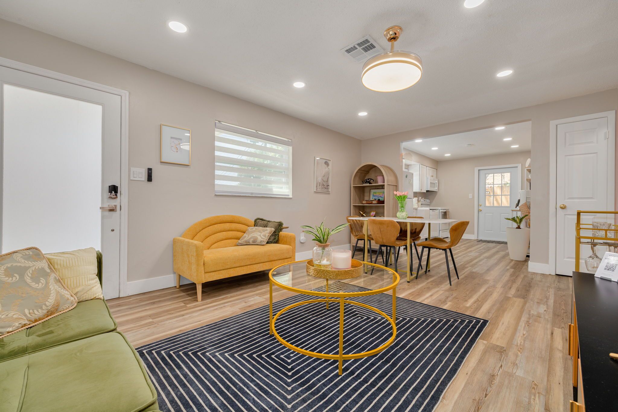 A modern living room with a sofa, coffee table, and dining area.