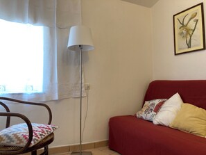 A room with a red sofa, patterned cushions, a floor lamp, and a framed botanical print on the wall. - Relaxation and culture, blending history and nature in Umbria’s most beautiful spots. (Acera)