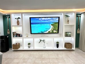 A modern living room with a flat-screen TV mounted on a white entertainment unit. - Luxury Beachside Condo - 3 Minutes walk to Bibijagua Bavaro Beach & Activities (Punta Cana)