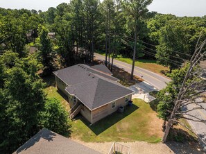 A residential house with a sloped roof, a front porch, and a driveway. - The Veloshire | Hot Tub + Back 40 Access (Bella Vista)