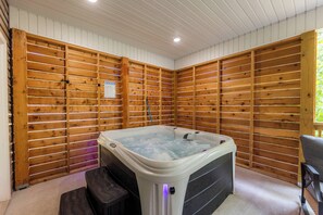 A hot tub in a room with wooden panel walls and a ceiling with recessed lighting. - The Veloshire | Hot Tub + Back 40 Access (Bella Vista)