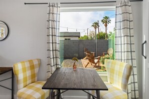 Una stanza con un divano a quadretti, un tavolo in legno e vista su un cortile con patio e mobili da esterno.
