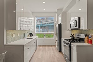 Una cocina moderna con un ventanal grande, electrodomésticos de acero inoxidable y vista a una obra en construcción.