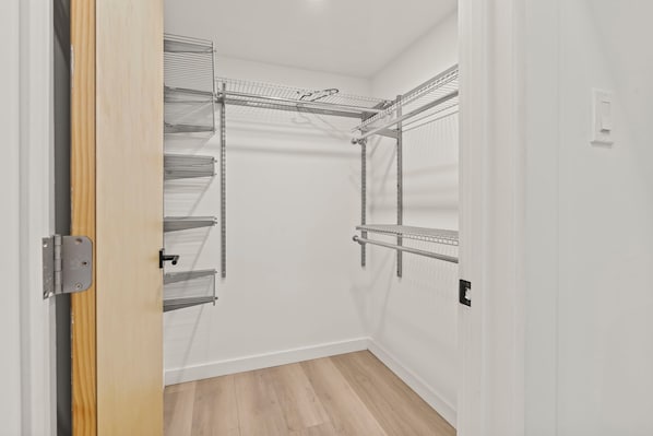 A walk-in closet with metal shelving units and a wooden floor.