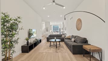 Una sala de estar moderna con un sofá, una mesa de centro y un televisor sobre un mueble.