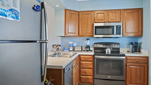 A kitchen with wooden cabinets, stainless steel appliances including a refrigerator, microwave, and oven, a sink, and a dishwasher. - 🌊Walk 2 Beach~2 Pools~Beautiful Views~2BR The Islander 314 🌊 (Destin)