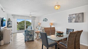 A spacious living area with a dining table, wicker chairs, and a ceiling fan. - 🌊Walk 2 Beach~2 Pools~Beautiful Views~2BR The Islander 314 🌊 (Destin)