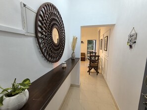 A hallway with a decorative wall piece, a plant, and a wooden chair. - Welcome to Su Casa, your serene escape 600m away from the sun-kissed shores (Candolim)