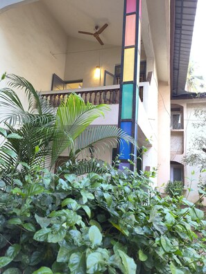 A multi-level building with a balcony, a ceiling fan, and lush greenery. - Welcome to Su Casa, your serene escape 600m away from the sun-kissed shores (Candolim)