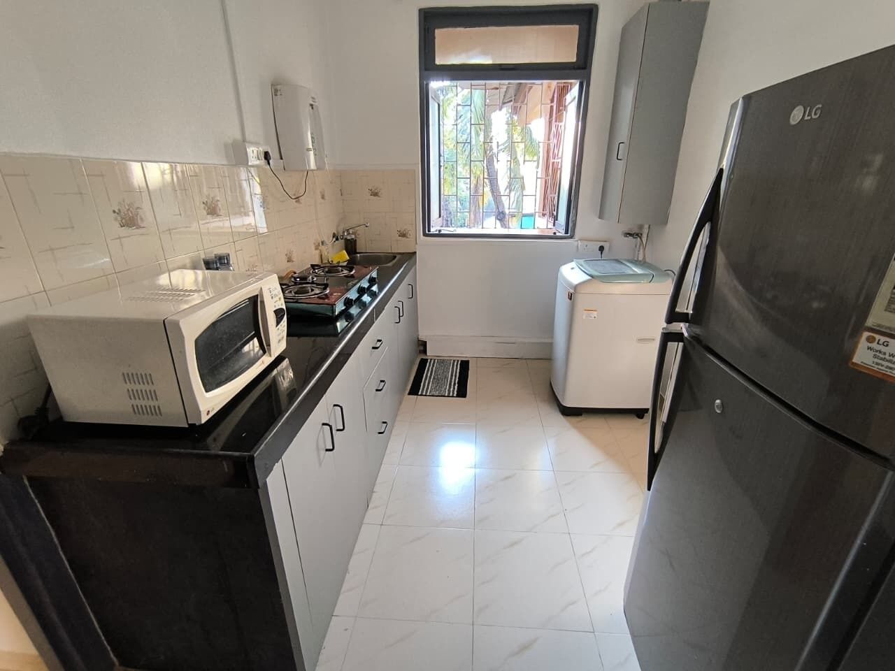 A compact kitchen with a microwave, stove, sink, and refrigerator.