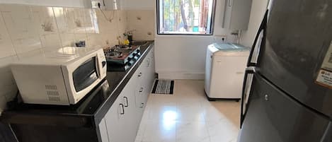 A compact kitchen with a microwave, stove, sink, and refrigerator.