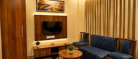 Una sala de estar con sofá, televisión, mueble de madera y piso estampado.