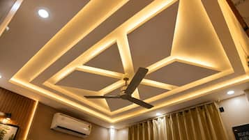 A ceiling with geometric lighting design, a ceiling fan, and an air conditioning unit.