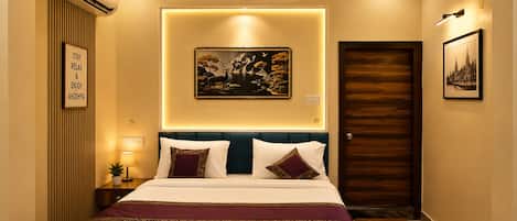 Una camera d'albergo con un letto, un condizionatore d'aria a muro, un quadro incorniciato e una porta.