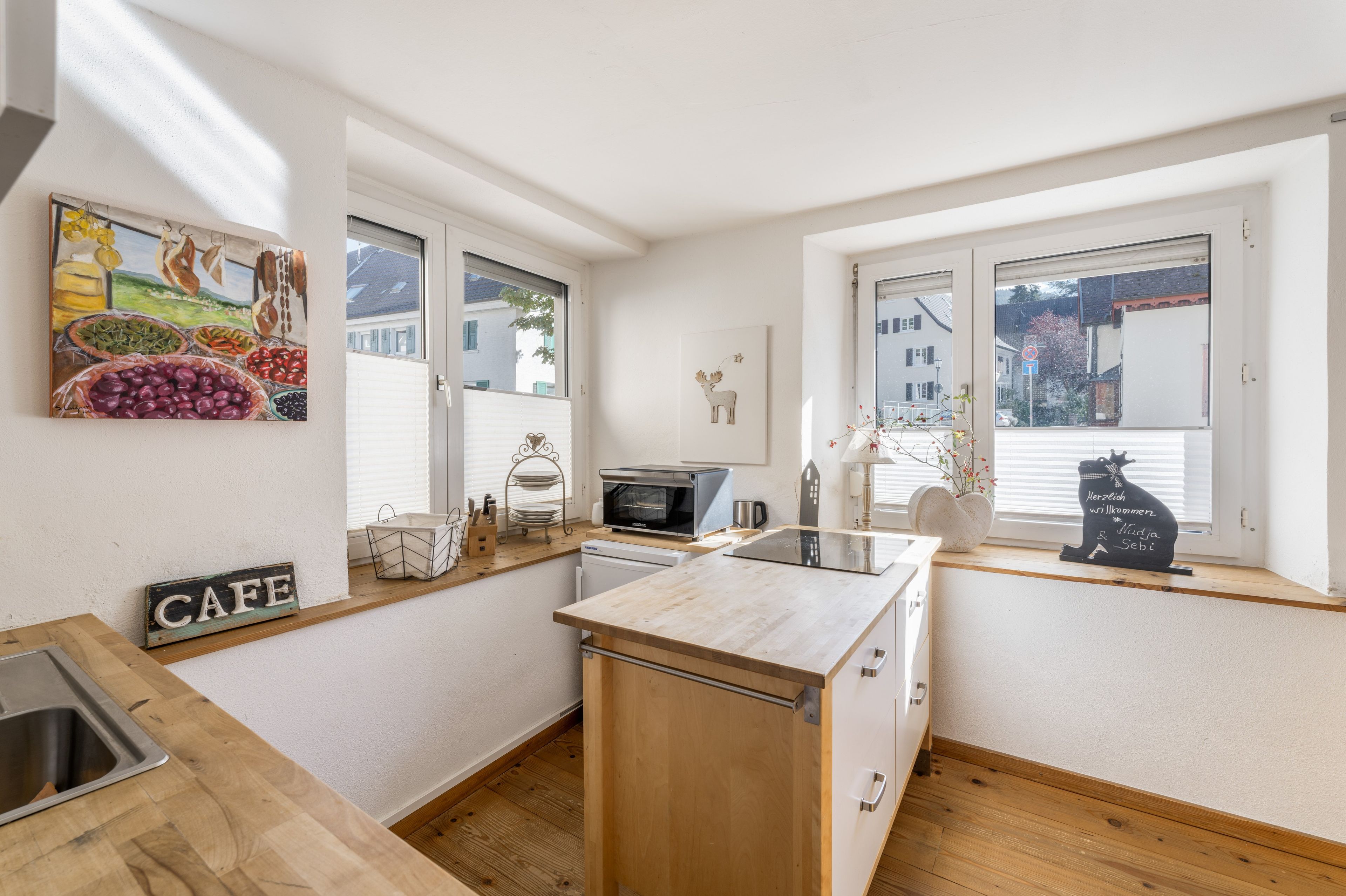 Eine moderne Küche mit Holzausstattung, einem eingebauten Ofen und einem Fenster mit Blick auf Häuser.