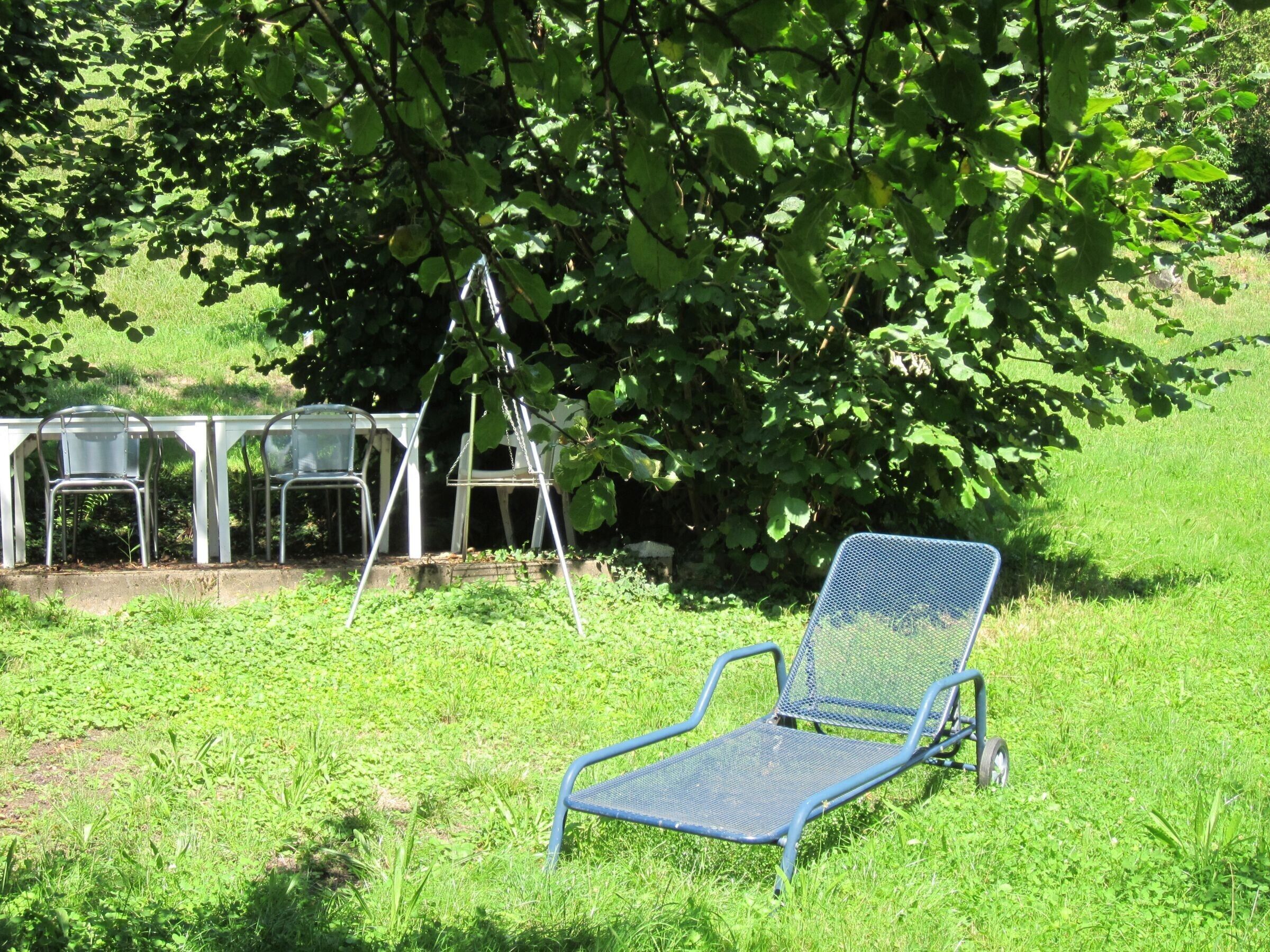 Un espace extérieur recouvert d’herbe, avec une chaise et une table en métal.