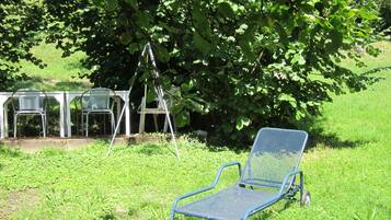 Un espace extérieur recouvert d’herbe, avec une chaise et une table en métal.
