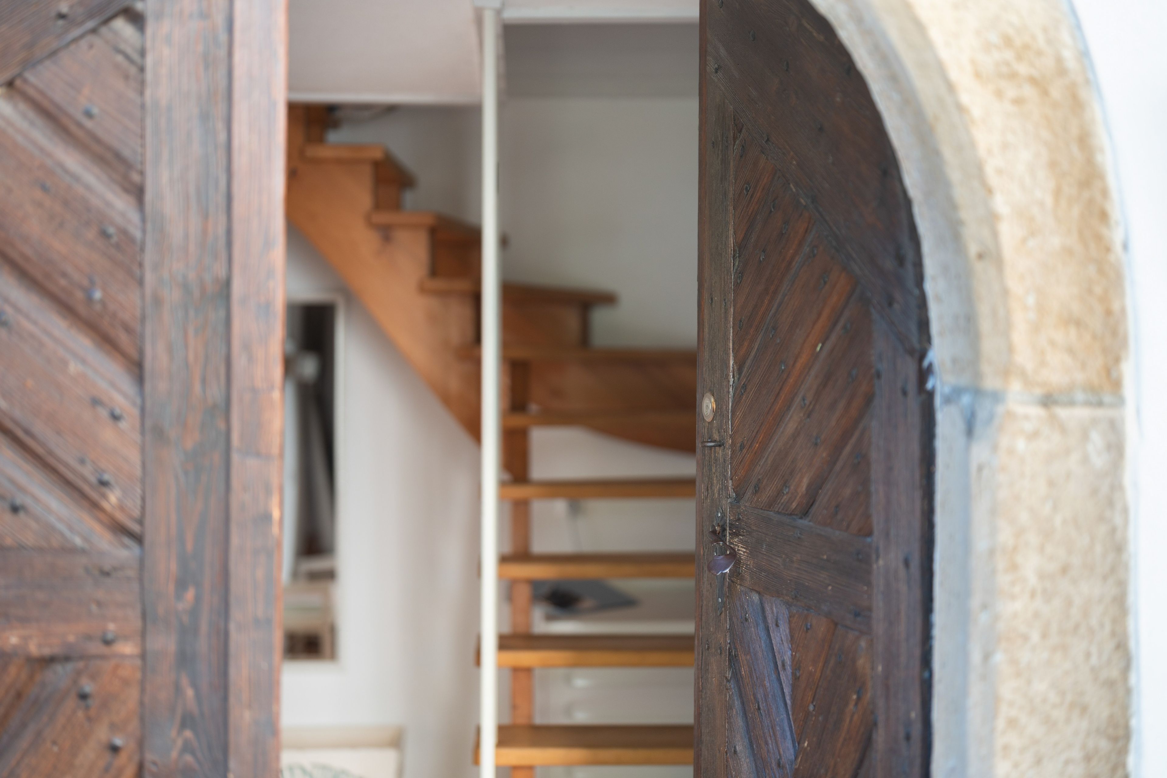 Una puerta de madera con diseño rústico, que da a una escalera con escalones de madera.