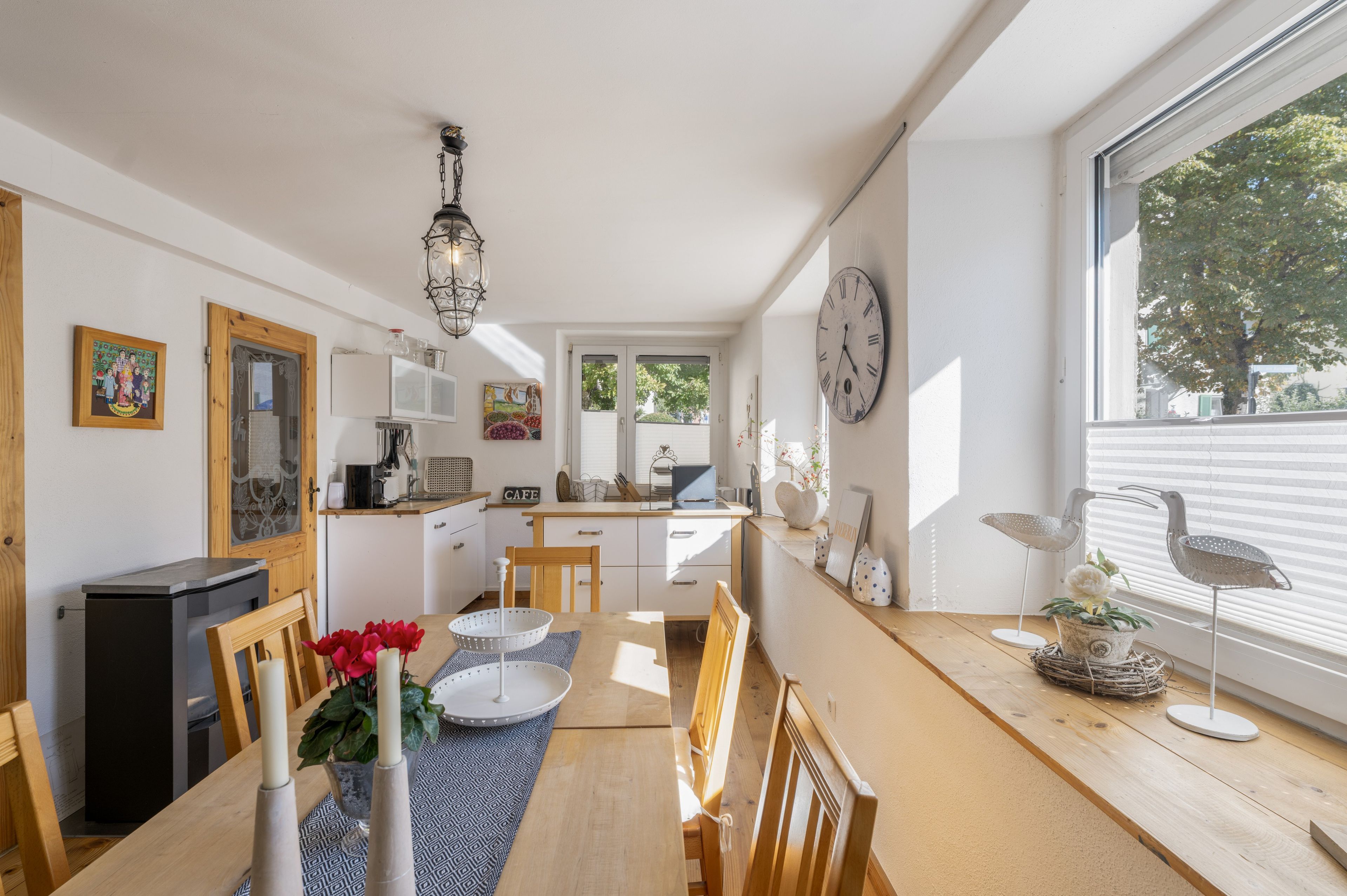 Eine helle Küche mit Essbereich, Holzmöbeln und einem großen Fenster.