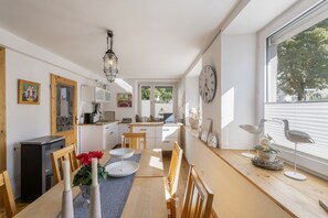 Een goed verlichte keuken met een eethoek, houten meubels en een groot raam.