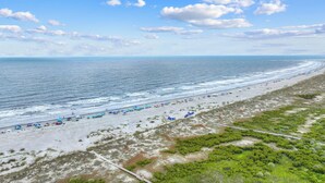 A beach with a clear sky, waves, and umbrellas.