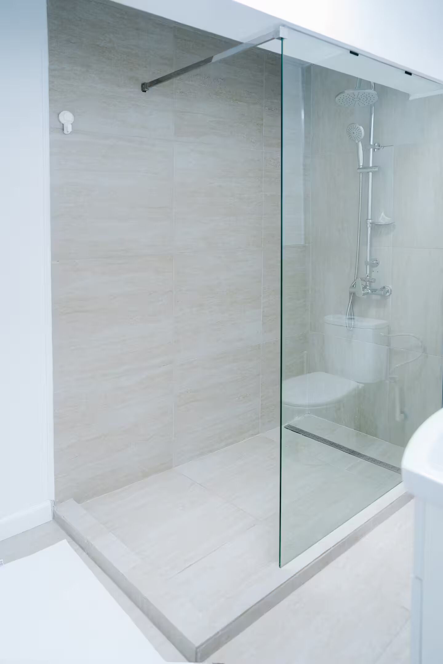 A modern bathroom with a glass-enclosed shower, a toilet, and a visible showerhead.