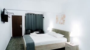Ein Hotelzimmer mit Bett, Nachttischen, Schreibtisch, Stuhl, Kleiderschrank, Fernseher und Vorhang.