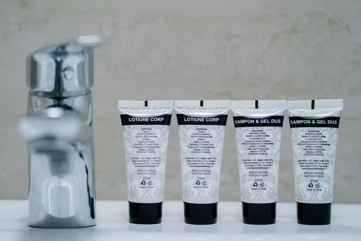 Fire toiletartikler mærket 'LOTIUNE CORP' og 'SAMPON & GEL DUS' med en vandhane i baggrunden.
