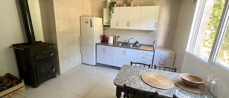 Una cocina con gabinetes blancos, una estufa y una mesa de comedor con sillas.