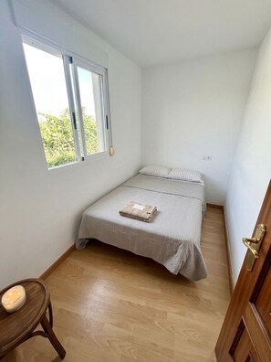 A small, single-bed room with a wooden floor, a window, and a door. - Cozy House & Garden, A Pedreira Slow Living (Celanova)
