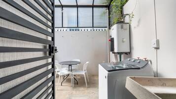 Een compacte kamer met een wasmachine, een klein tafeltje met stoelen en een waterkoker.