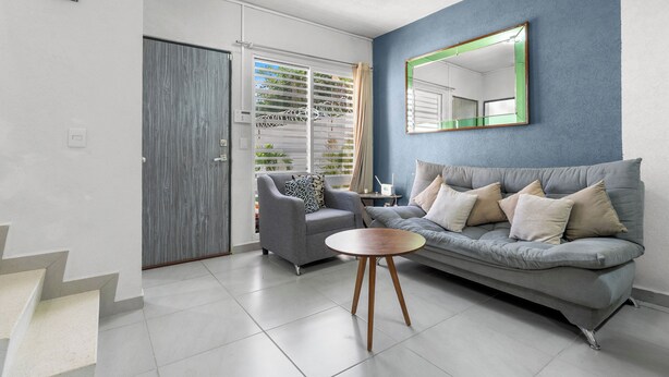 A modern living room with a grey sofa, a round wooden coffee table, and a grey armchair.