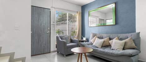 Una sala de estar moderna con un sofá gris, una mesa de centro redonda de madera y un sillón gris.