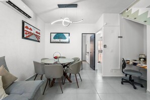 A modern dining area with a round table, grey chairs, and a ceiling light fixture. - Casa Esperanza Zafiro Residencial (San Vicente)