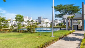 A residential area with a swimming pool, green lawns, and modern buildings.