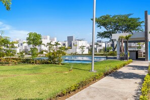 A residential area with a swimming pool, green lawns, and modern buildings. - Casa Esperanza Zafiro Residencial (San Vicente)