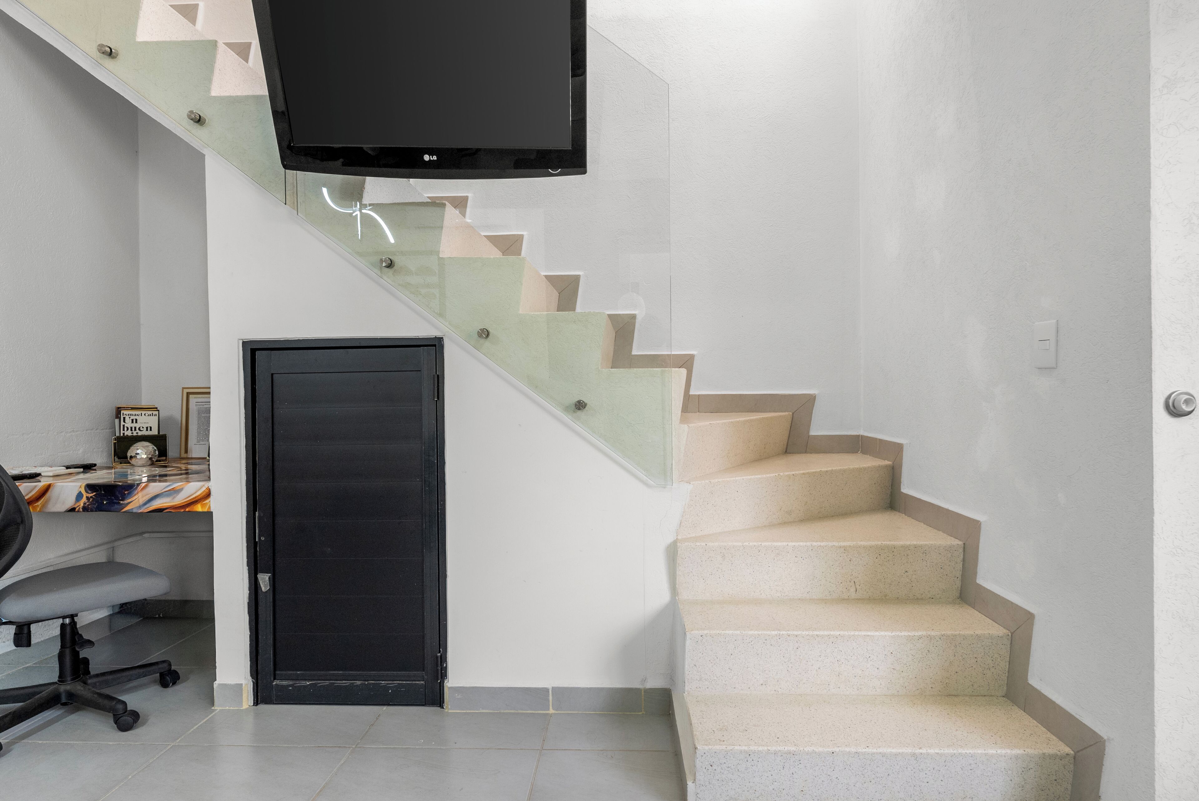 A staircase with a flat design, a black door, and a television mounted above it.