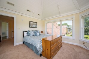 A bedroom with a bed, dresser, and large windows. - Stylish Lakefront Deep Creek Retreat w/ Hot Tub (Swanton)