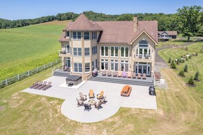 A large two-story house with a patio area featuring outdoor furniture and a fire pit. - Stylish Lakefront Deep Creek Retreat w/ Hot Tub (Swanton)