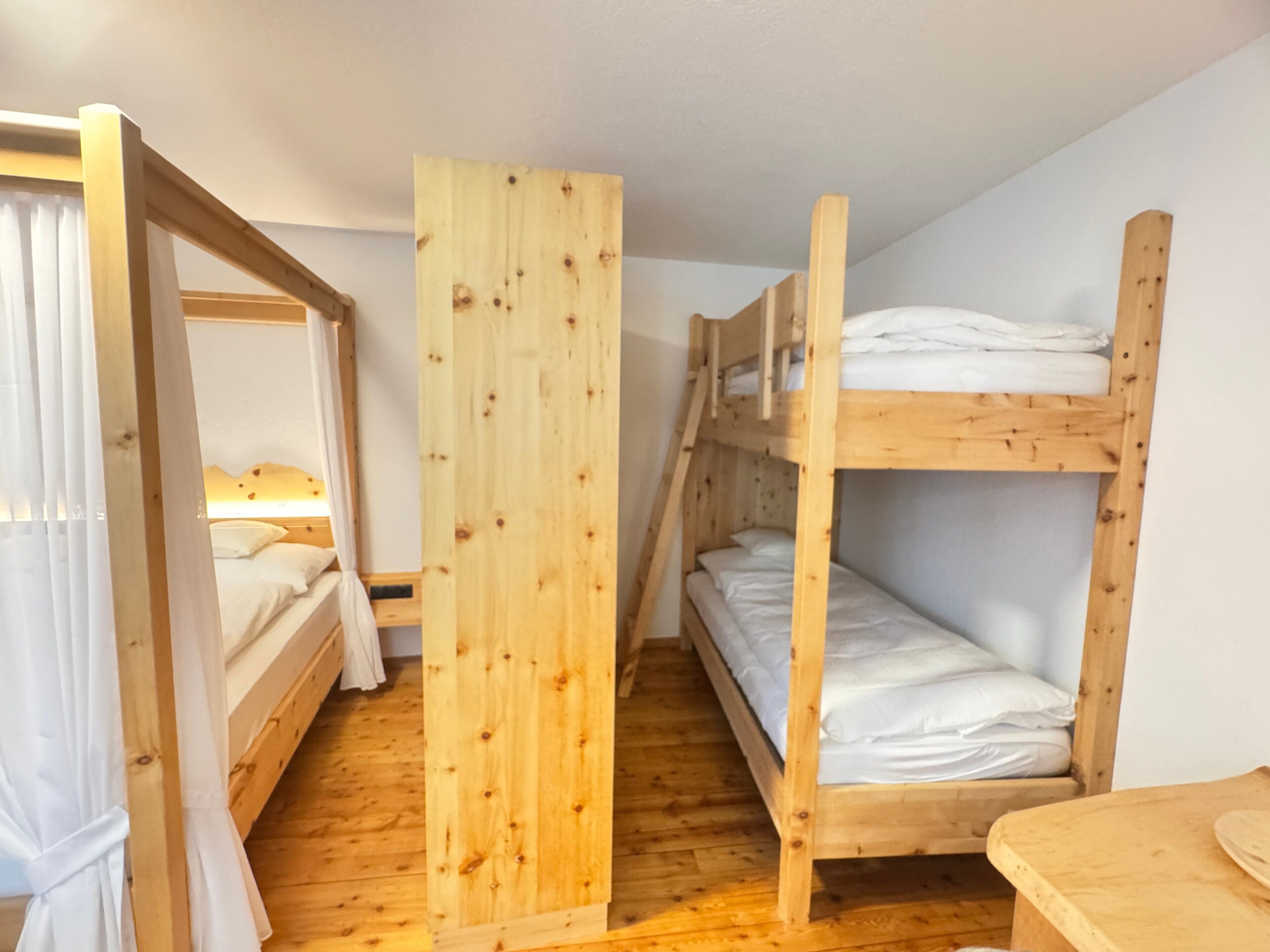 Ein Zimmer mit Stockbetten, einer Holzablage und einem kleinen Tisch.
