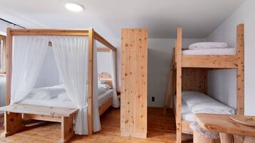 Una stanza con due letti a castello in legno, un tavolo di legno e una finestra con tende.