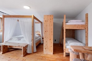 Una habitació amb dos llits superposats de fusta, una taula de fusta i una finestra amb cortines.
