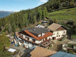 Zona residencial amb cases, un camí asfaltat i un turó cobert de bosc.