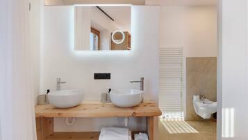 Ein modernes Badezimmer mit zwei Waschbecken, einem Holz-Waschtisch, einem Spiegel und einem Handtuchhalter.