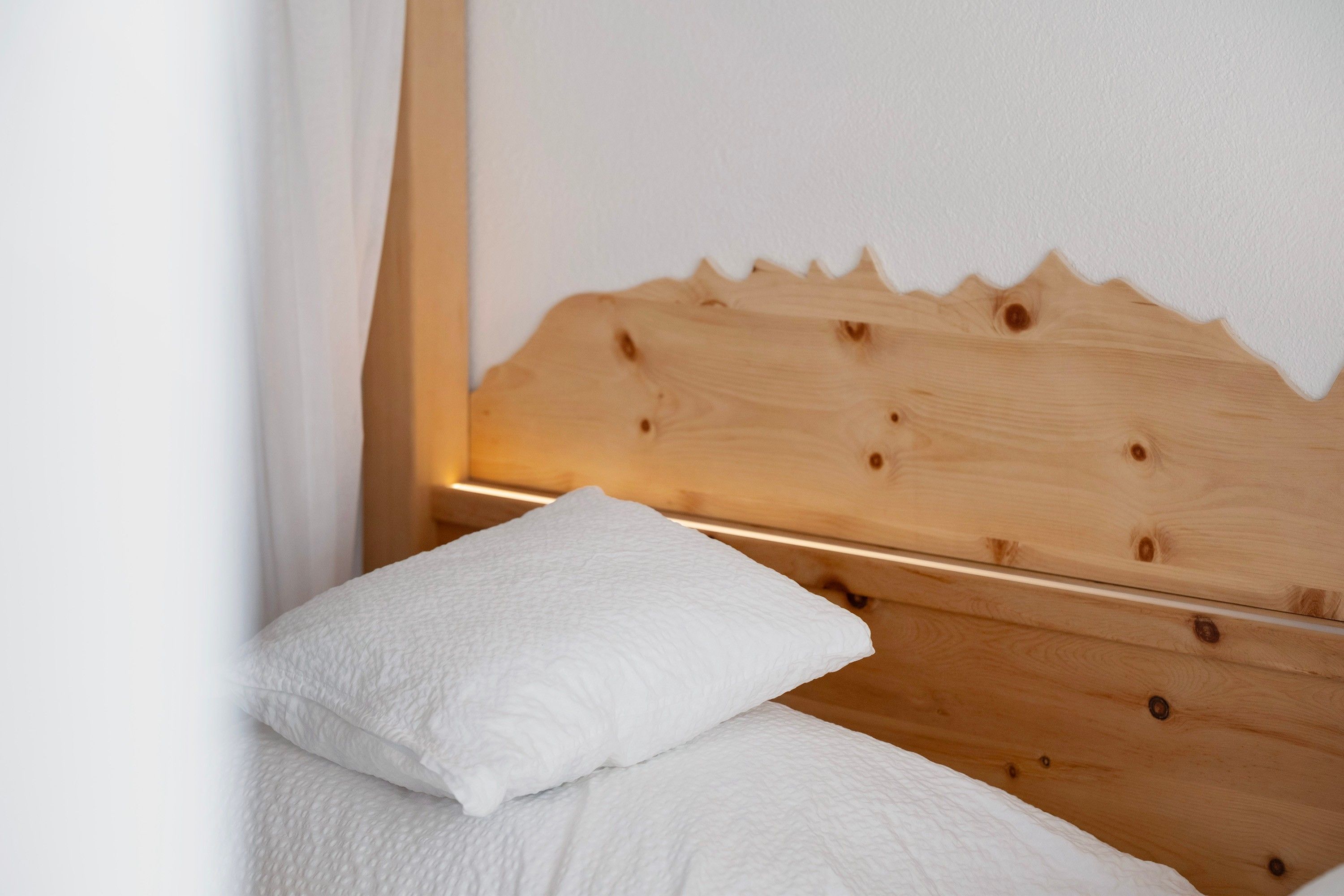 Ein Bett mit einem hölzernen Kopfteil und zwei Kissen.