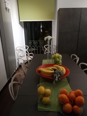 Una mesa de comedor con un frutero, un florero y un bol con naranjas.