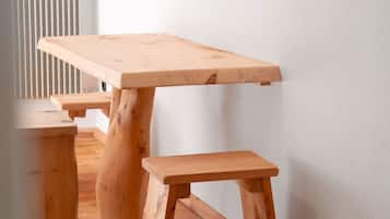 A wooden table with a bench, positioned against a white wall.