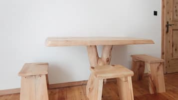 Ein schlichter Holztisch mit drei Beinen in einem Zimmer mit Holzboden und weißer Wand.